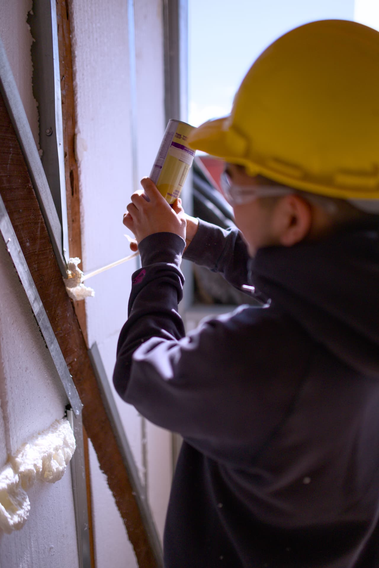 Trabajadora aplicando espuma selladora en la envolvente de la construcción