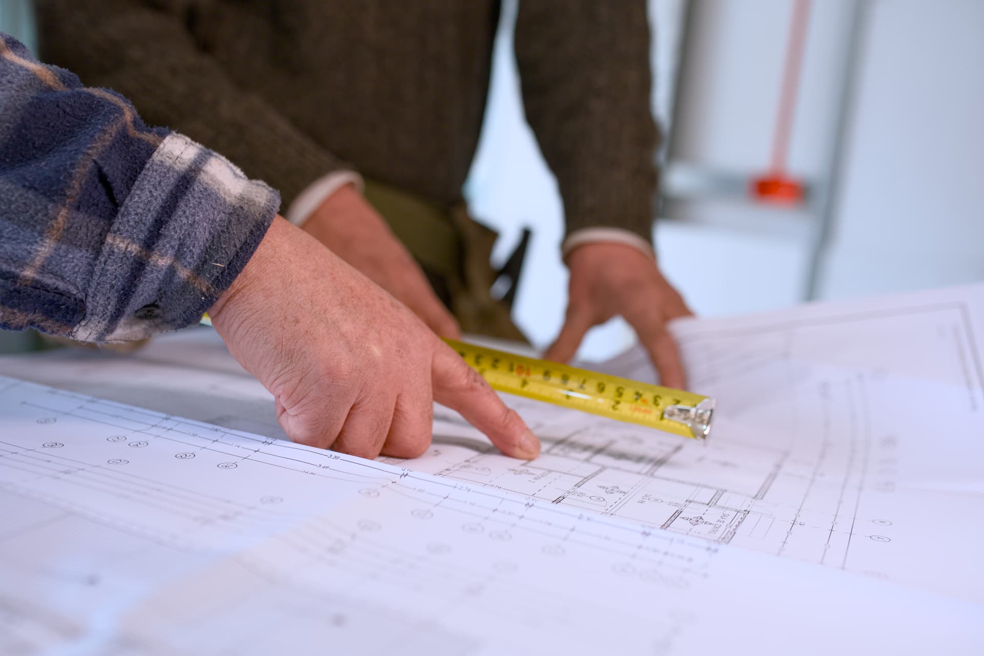 Profesional midiendo y verificando cotas sobre los planos del proyecto